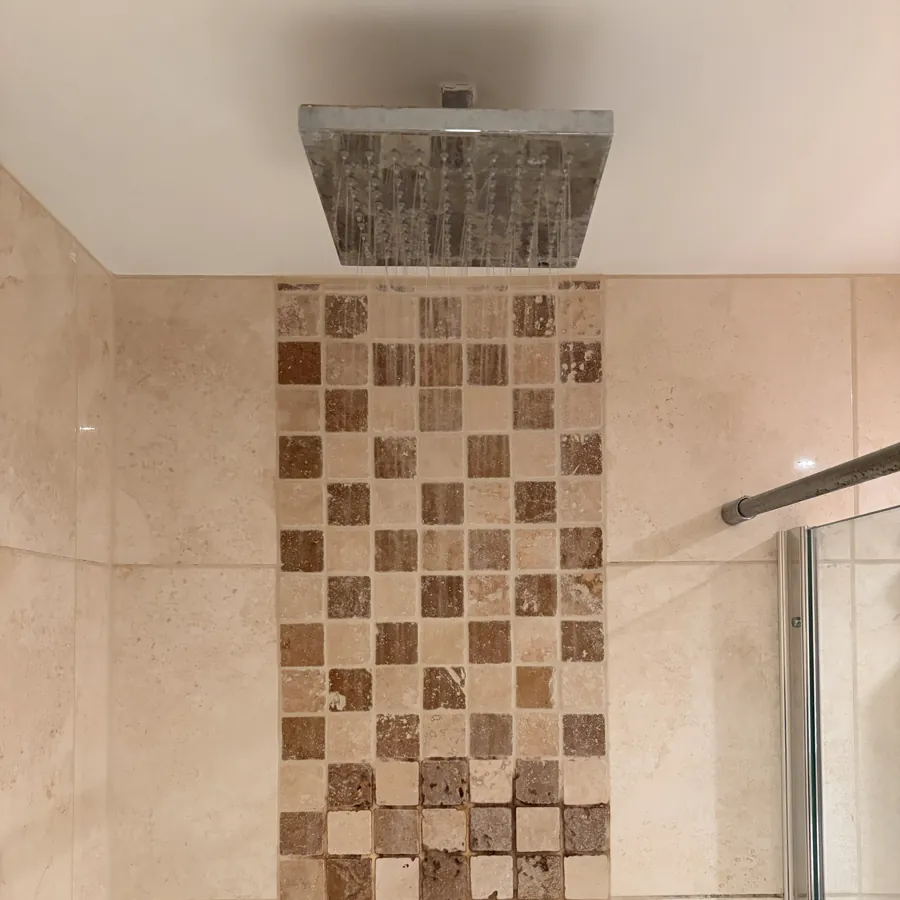 A rainfall shower in a tiled bathroom