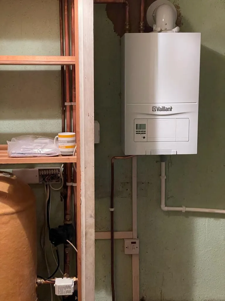 A new wall-hung boiler fitted beside an old copper hot water cylinder