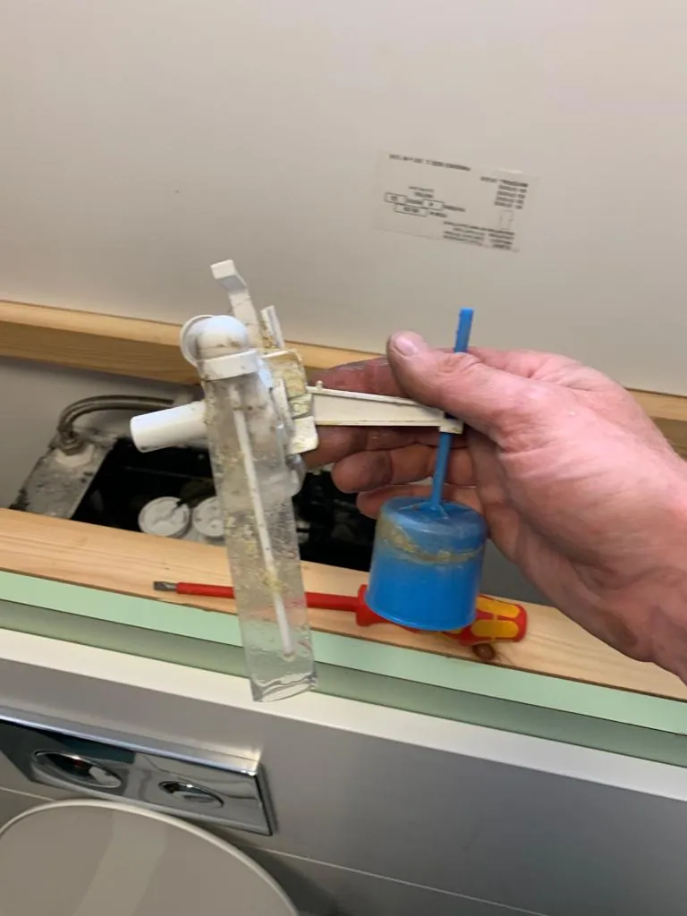 Engineer holding a toilet fill valve during replacement